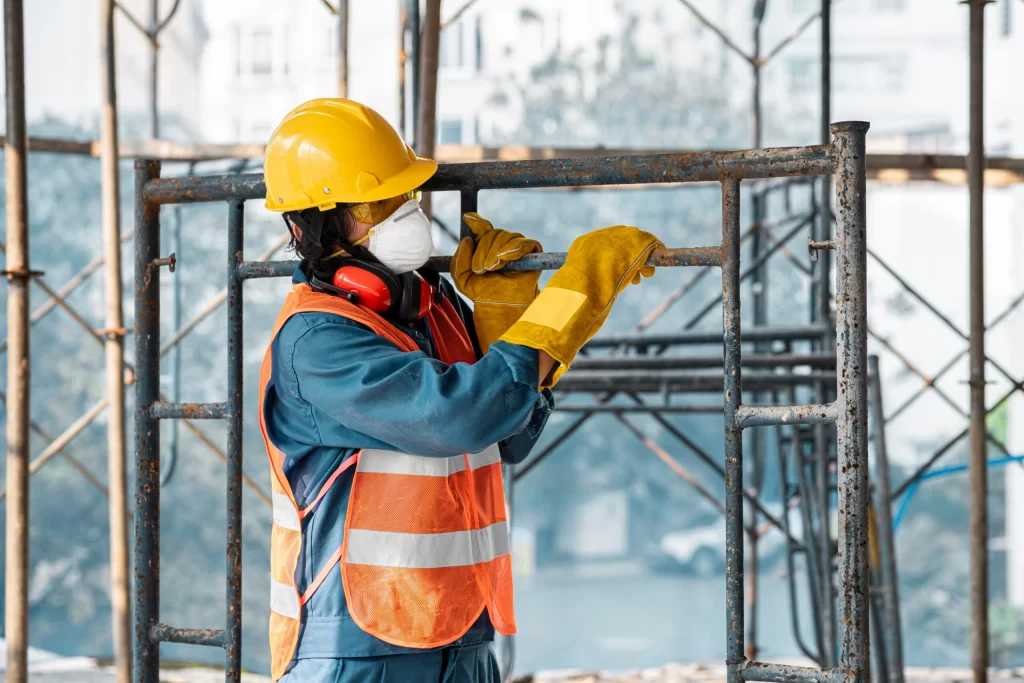 imagem de um construtor trabalhando em uma obra civil, carregando estruturas metálicas